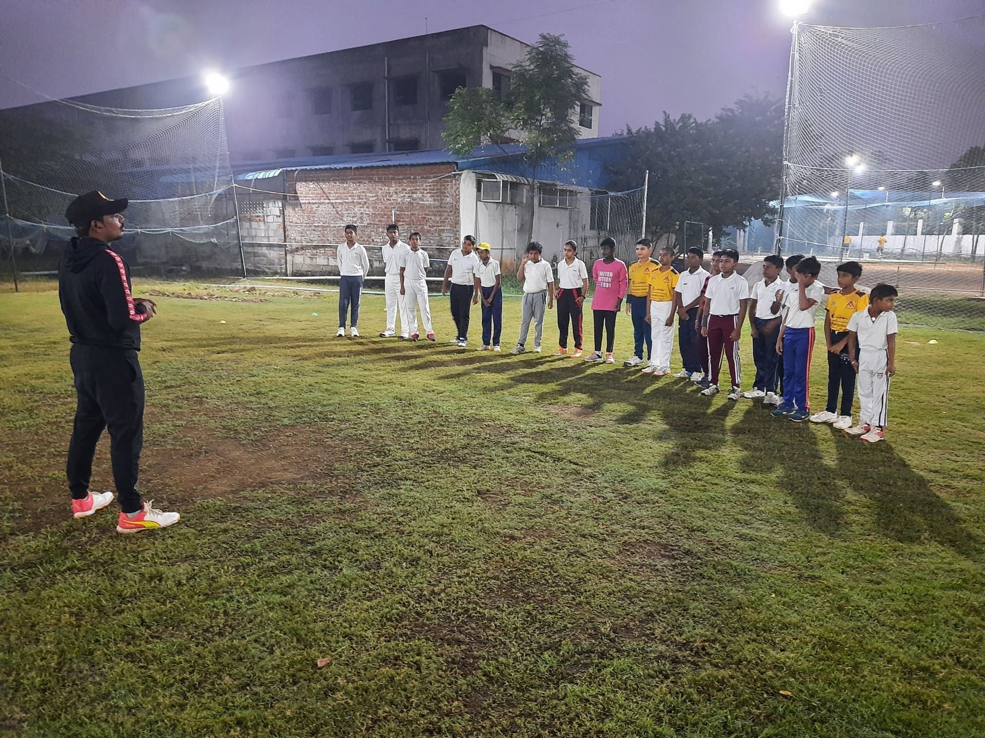 Coach briefing the junior squad at floodlit nets